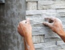 worker install stone wall surface with cement for house
