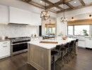 Kitchen Interior with Island, Sink, Cabinets, and Hardwood Floors in New Luxury Home. Includes elegant pendant light fixtures and wood beam ceiling